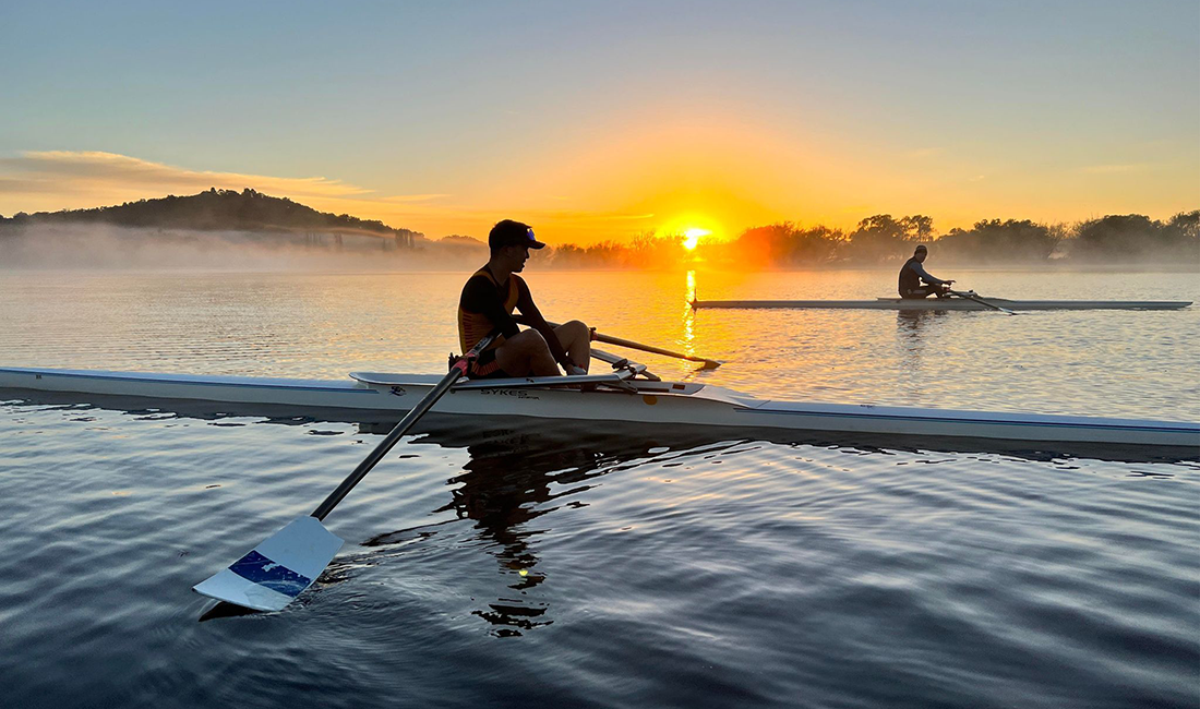 Person rowing at sunrise
