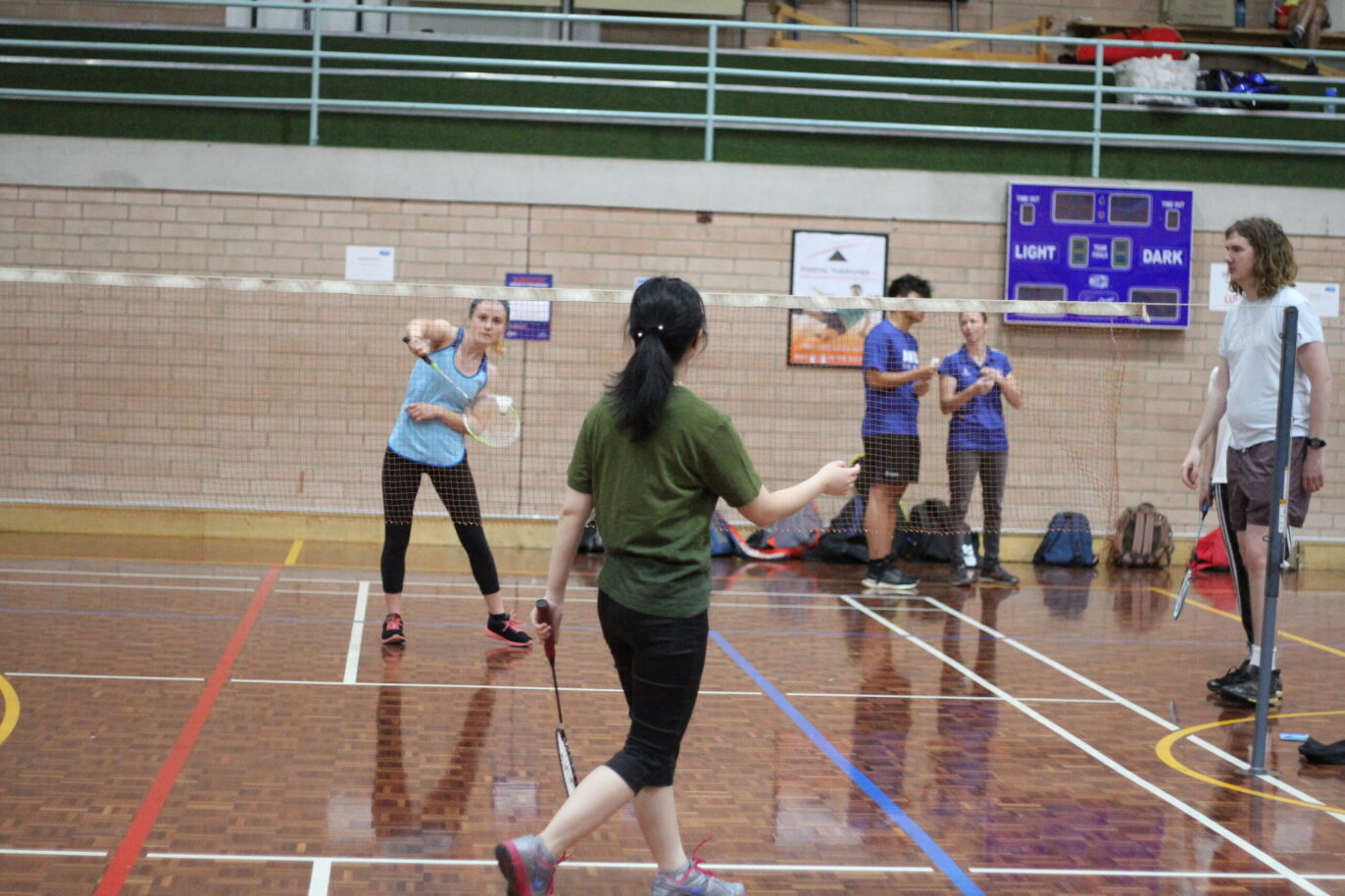Two women hitting a shuttlecock over a badminton net